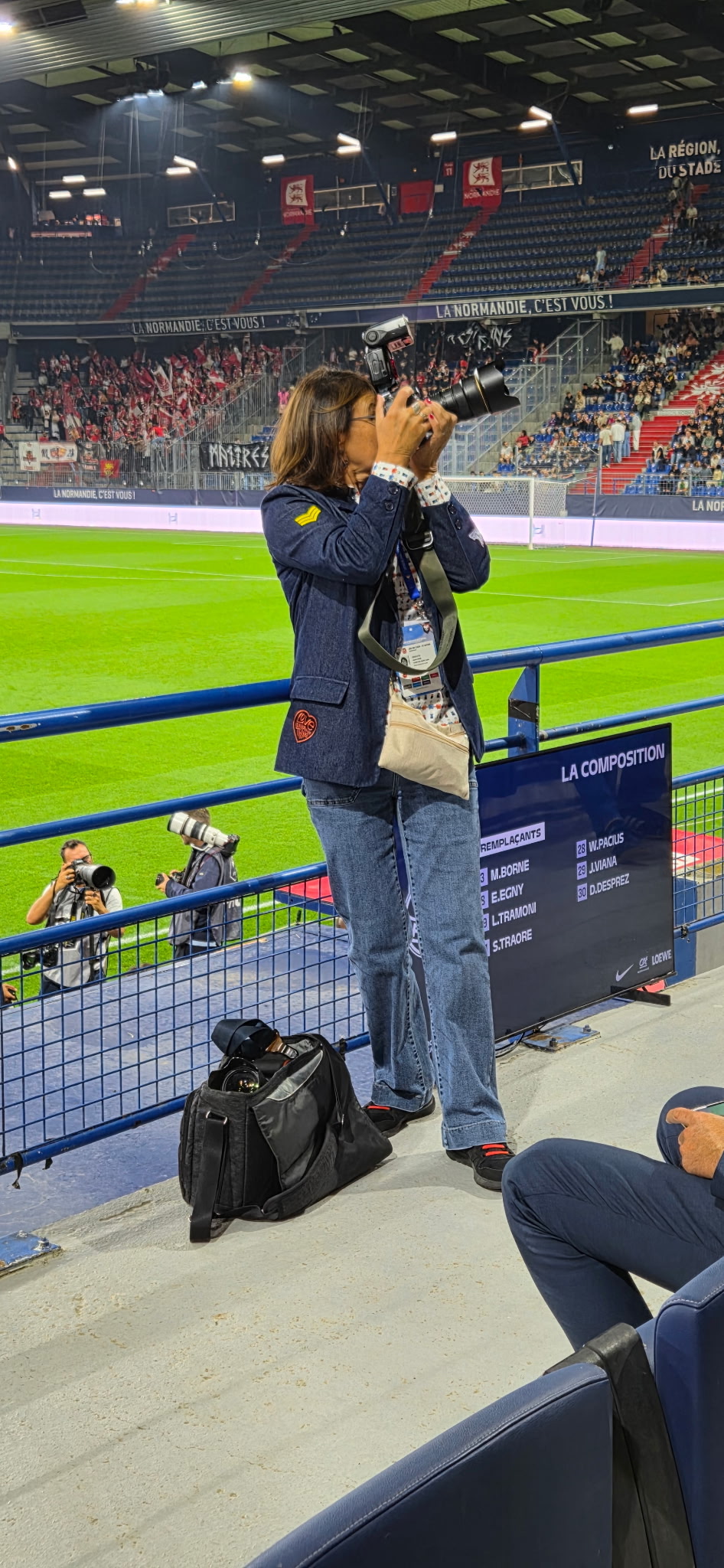 La photographe en pleine prise de vue dans les tribunes d’un stade.